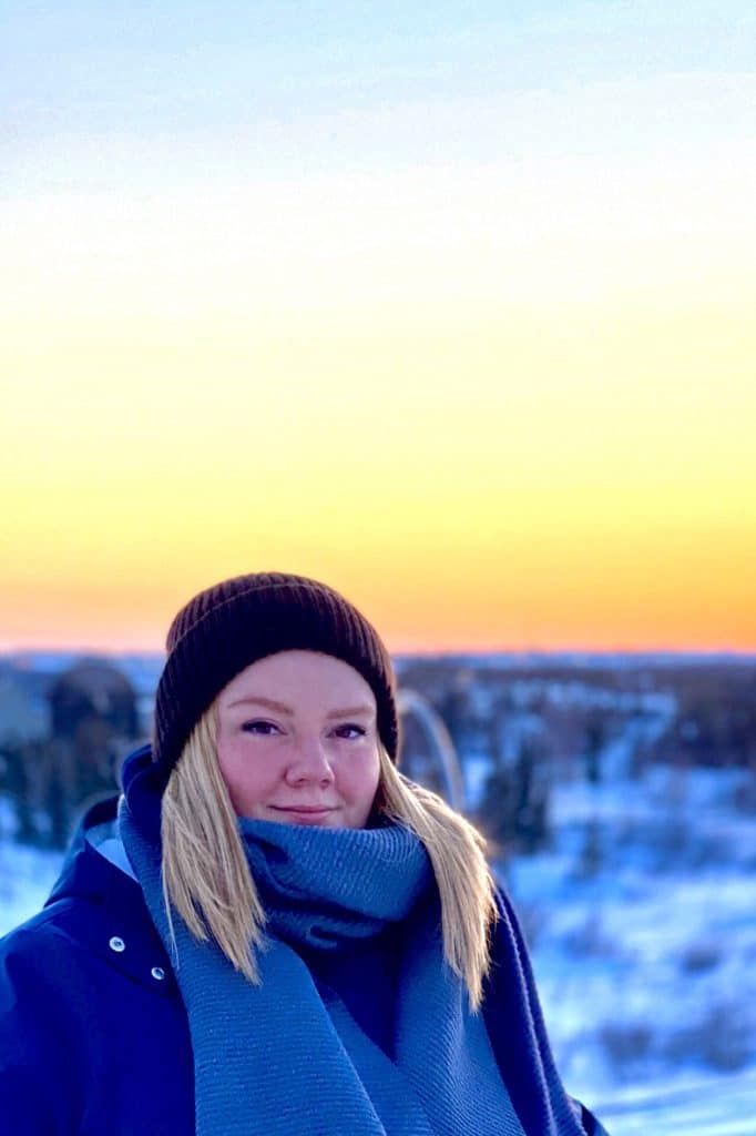 A winter photo of Samantha Gruber with a sunset in the background.